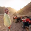 Young traveler standing beside quad bikes during desert off road adventures, preparing for an ATV ride through rocky desert landscapes at sunset.