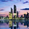 Abu Dhabi skyline at sunset reflected on calm water, showcasing modern skyscrapers during an Abu Dhabi private tour.