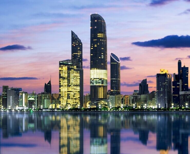 Abu Dhabi skyline at sunset reflected on calm water, showcasing modern skyscrapers during an Abu Dhabi private tour.