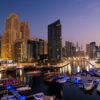 Dubai Private Tour showcasing Dubai Marina at night with luxury yachts, illuminated skyscrapers, and waterfront city lights reflecting on the canal.