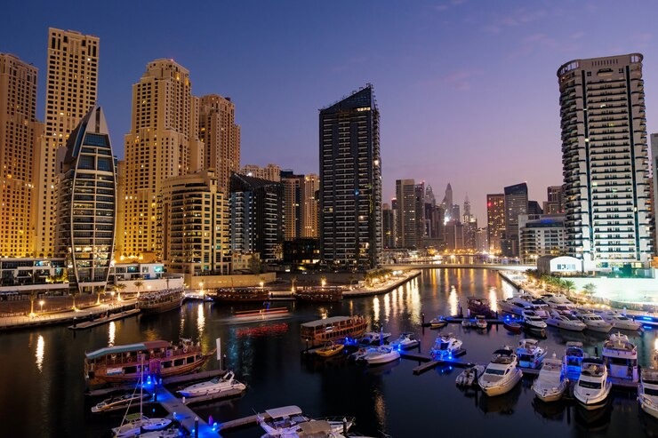 Dubai Private Tour showcasing Dubai Marina at night with luxury yachts, illuminated skyscrapers, and waterfront city lights reflecting on the canal.