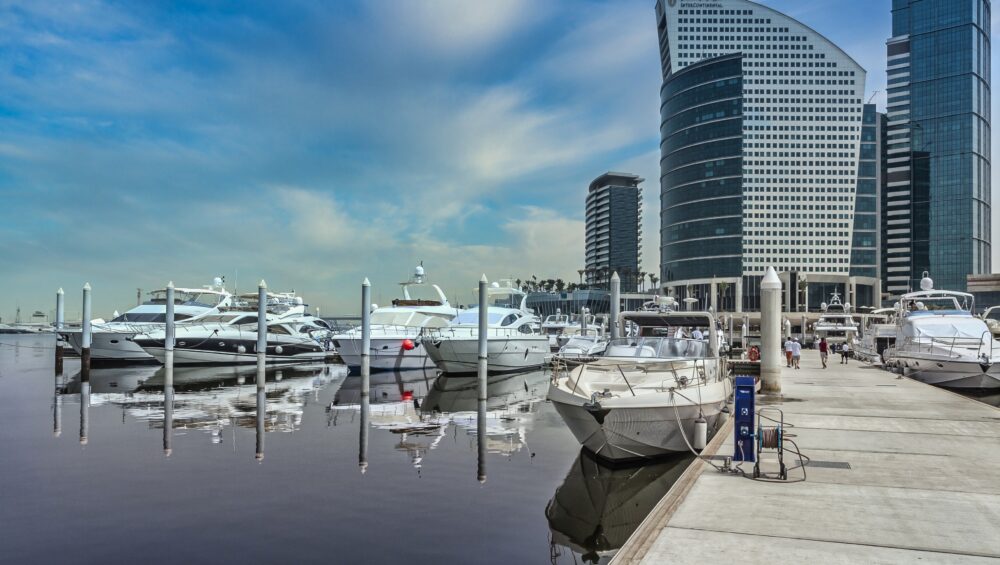Private Yacht Rental Dubai at a modern marina with luxury yachts docked beside Dubai’s waterfront skyline.