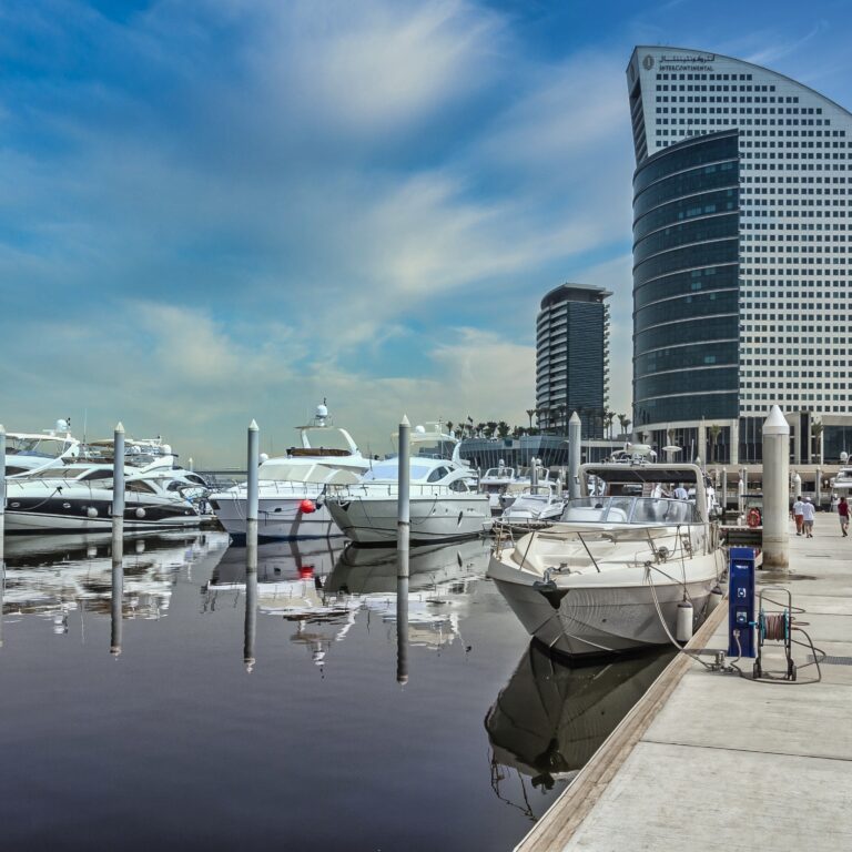 Private Yacht Rental Dubai at a modern marina with luxury yachts docked beside Dubai’s waterfront skyline.