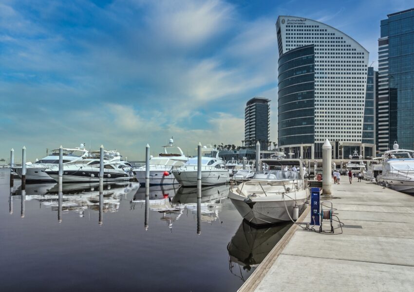 Private Yacht Rental Dubai at a modern marina with luxury yachts docked beside Dubai’s waterfront skyline.